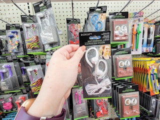 hand holding a pair of white over the ear ear buds