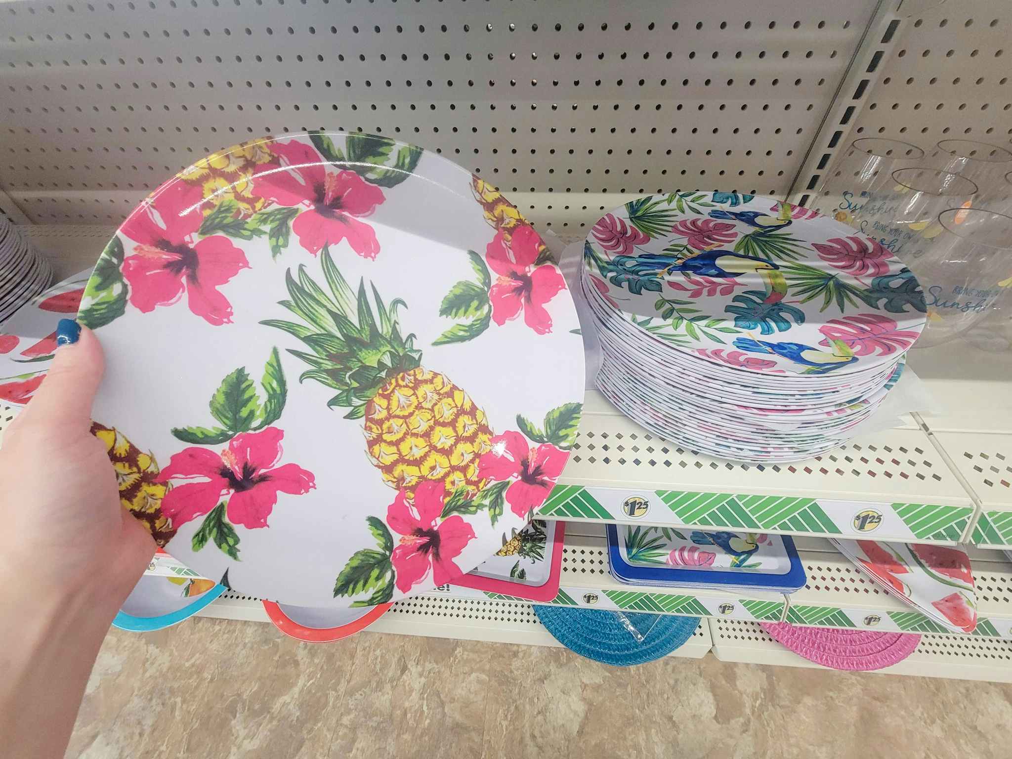 hand holding a plate with a pineapple and pink flowers on it