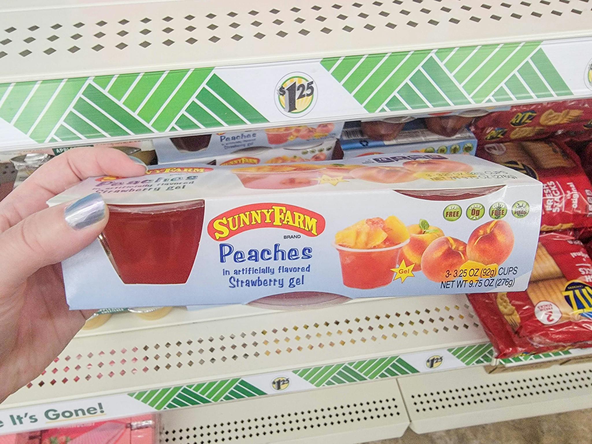 hand holding a pack of peaches in strawberry juice