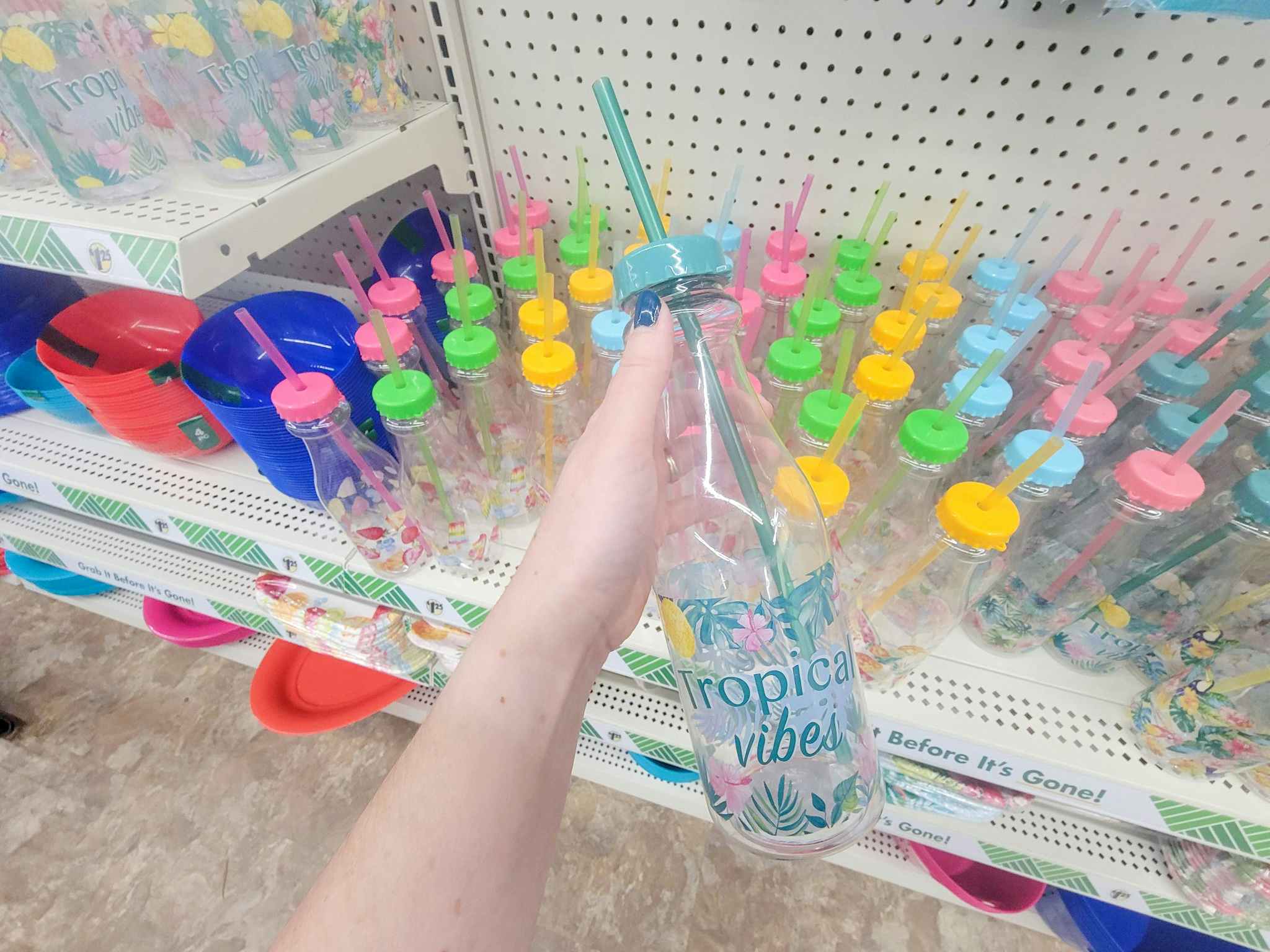 hand holding a cup with a straw that says tropical vibes
