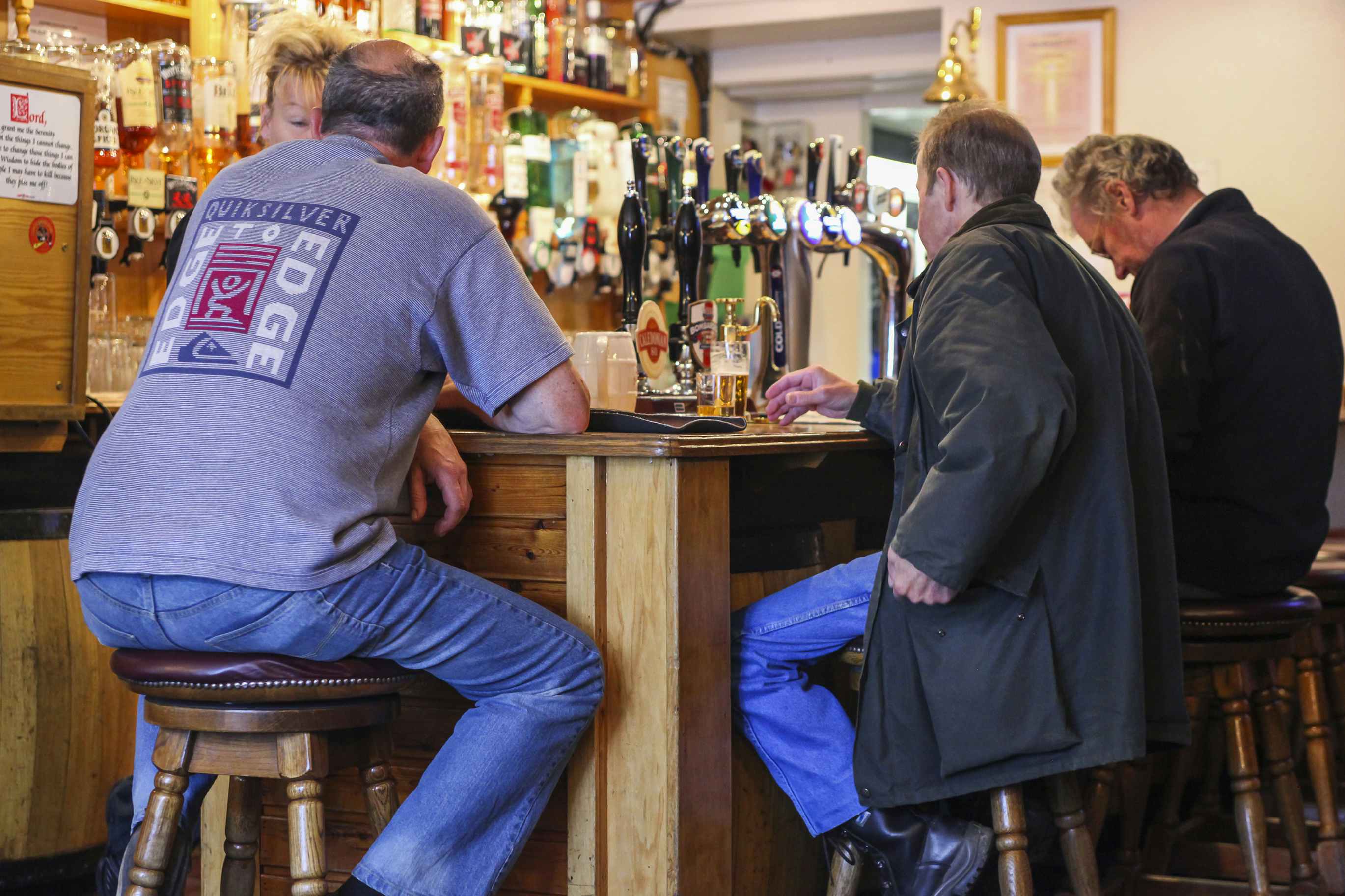 three men sitting at a bar drinking beer
