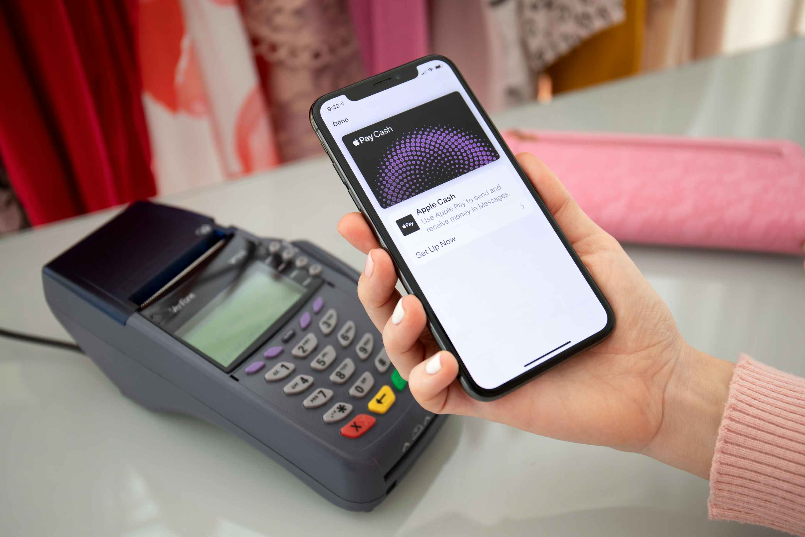 a woman holding her phone over a credit card terminal to pay for her order with Apple Pay