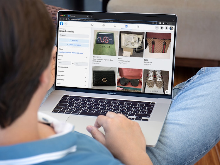 A person sitting on a couch, using a laptop that is displaying the Facebook Marketplace search results for Gucci.