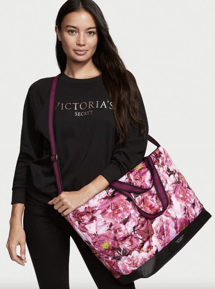 a woman carrying a floral victoria's secret weekender bag