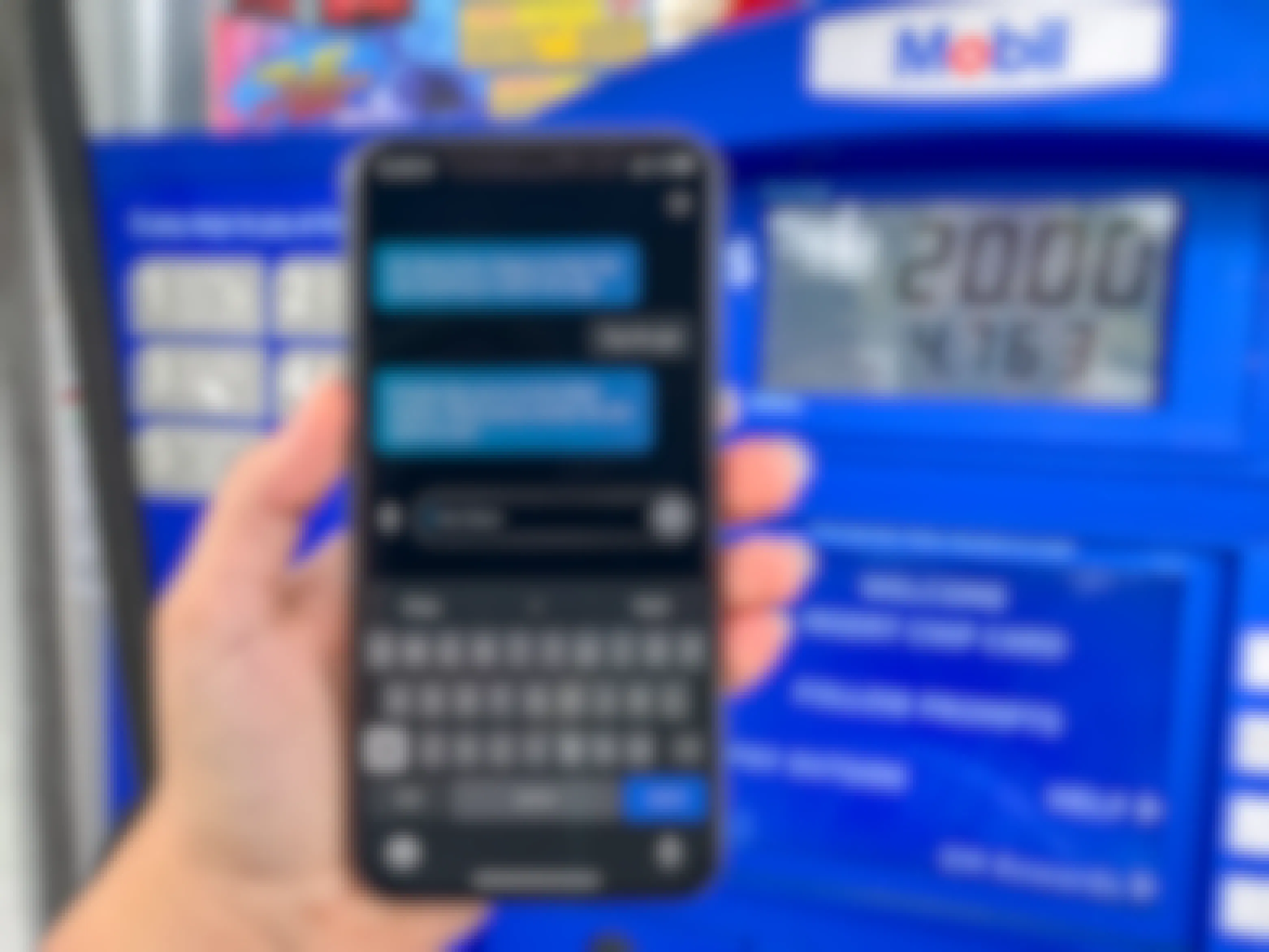A person's hand holding up their iPhone, using the Amazon Alexa app to pay for gas at a Mobil gas station pump.