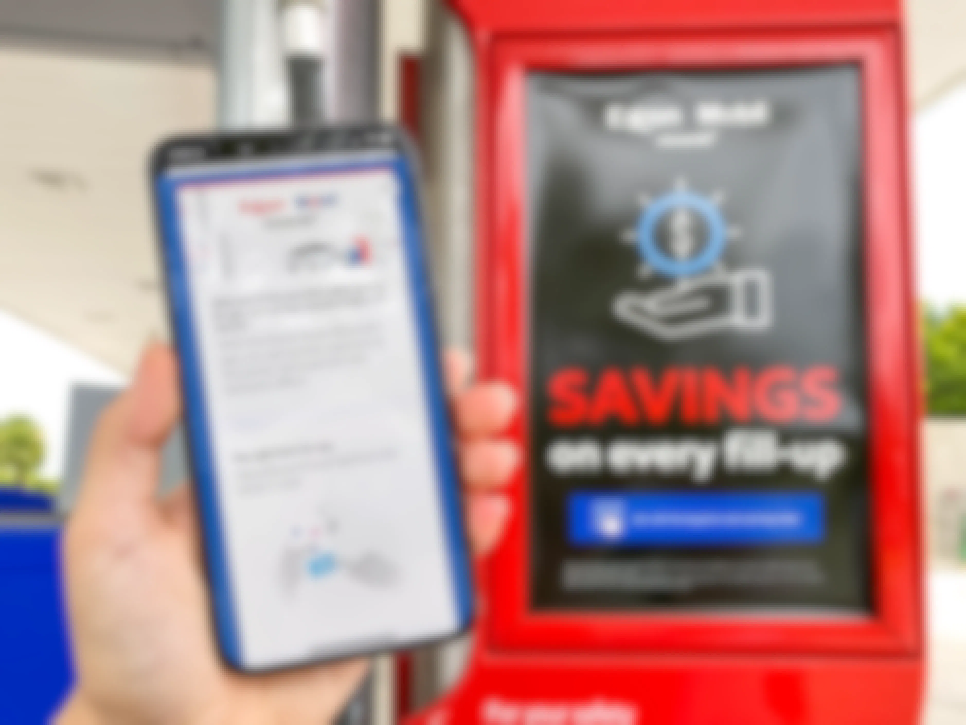 A person's hand holding up an iPhone displaying the Exxon Mobile rewards app near a sign advertising the rewards near a Mobil gas station pump.