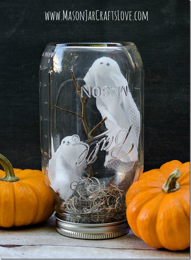 Upside down Mason Jar with a styrofoam ghost inside and moss at the bottom near the lid.