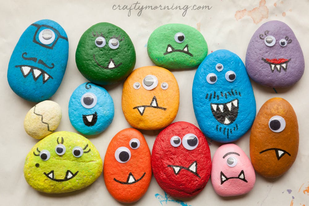 Multi-colored rocks painted with silly faces and with googly eyes.