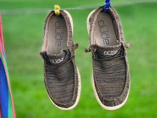 A pair of Hey Dude shoes hanging out to dry on a clothing line.