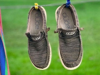 A pair of Hey Dude shoes hanging out to dry on a clothing line.