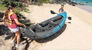 a couple carrying a kayak to the water