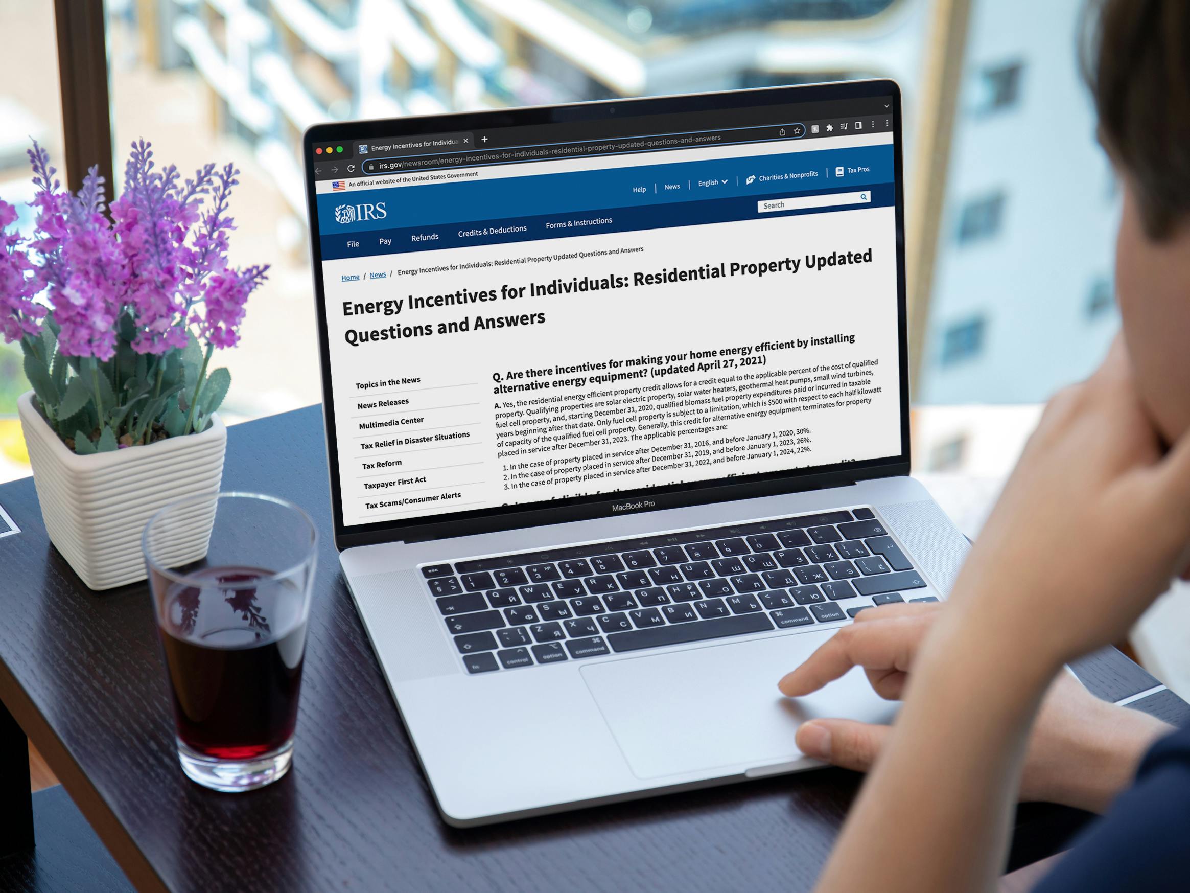 A person using a laptop displaying the IRS website's page for Energy Incentives for Individuals: Residential Property Updated Questions and Answers