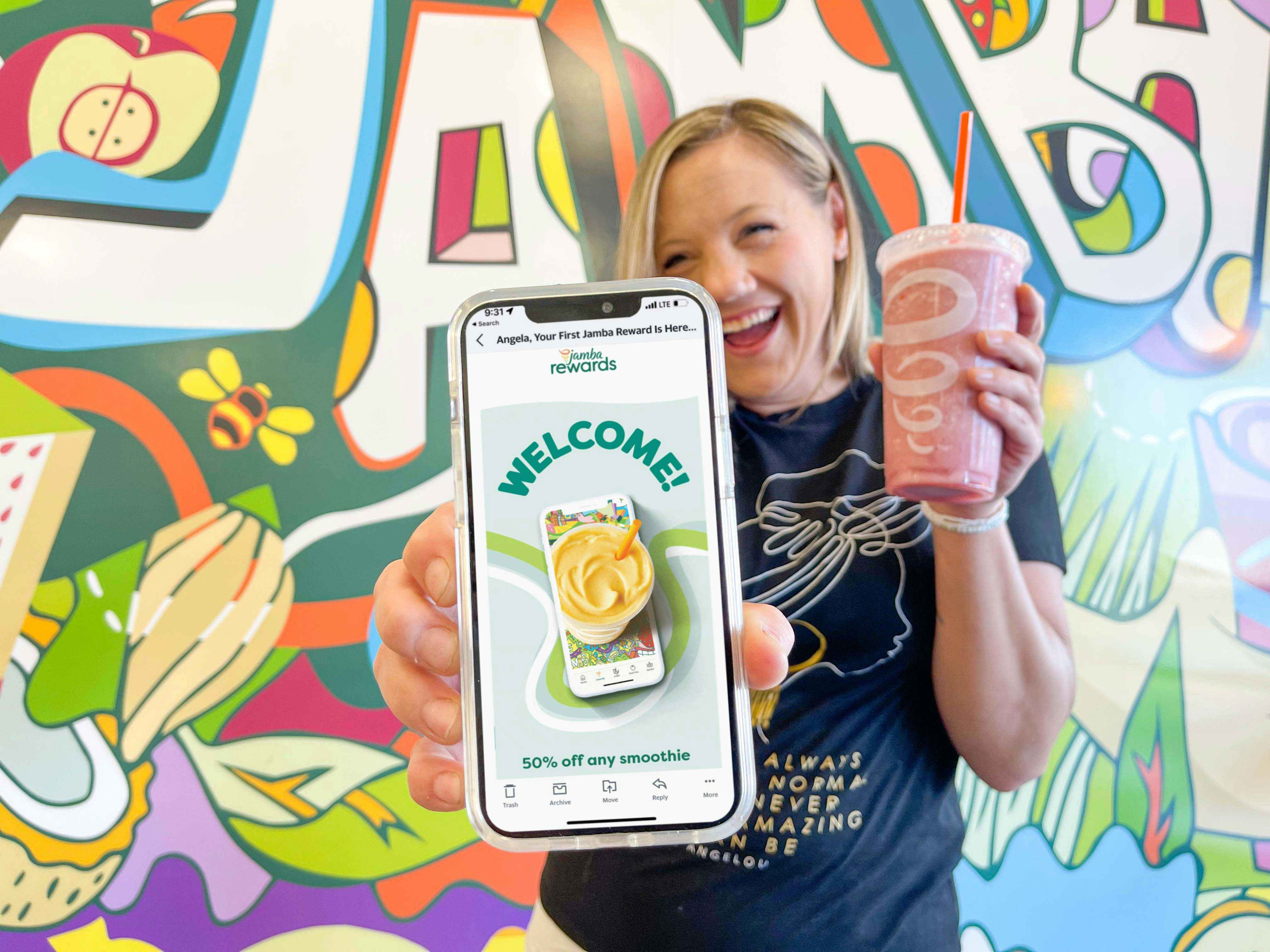 woman holding cellphone with rewards email and holding a juice in other hand 