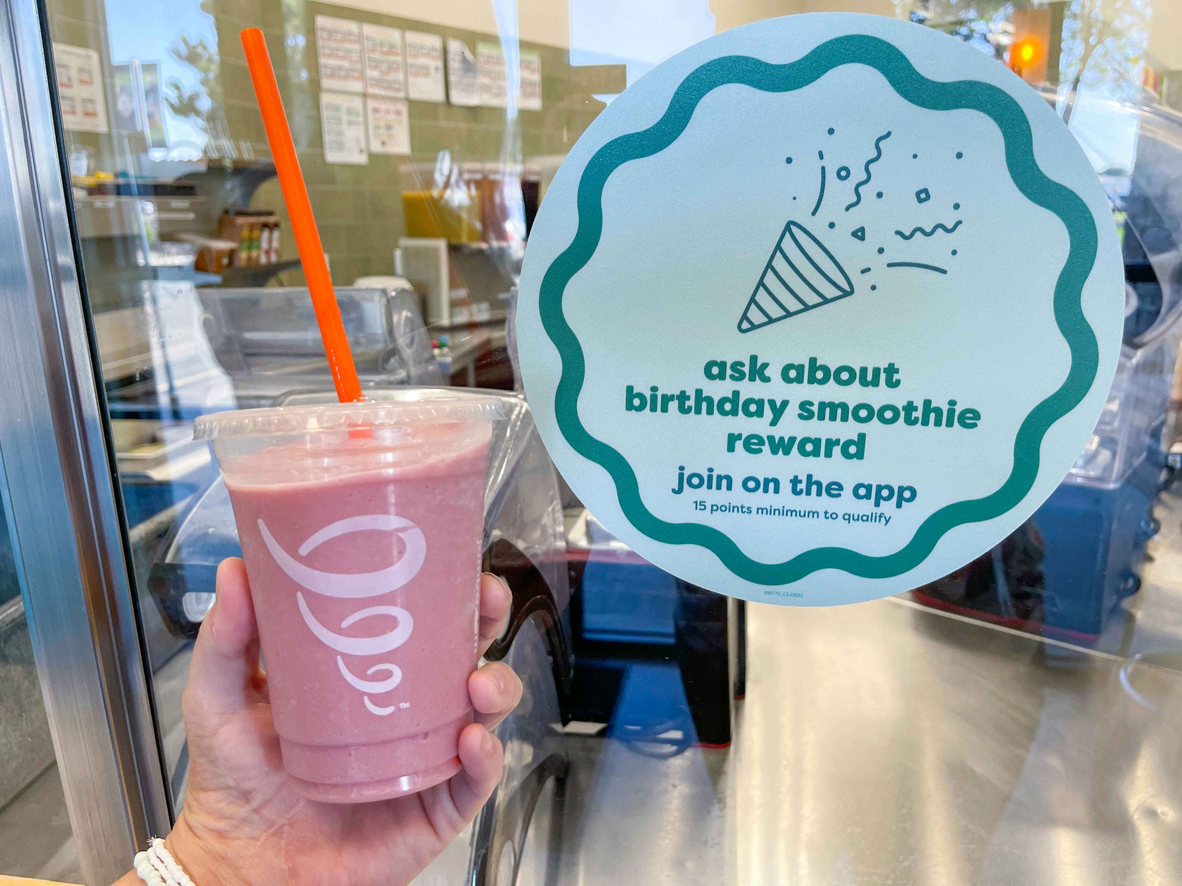 holding a smoothie on one hand and birthday smoothie reward sign 