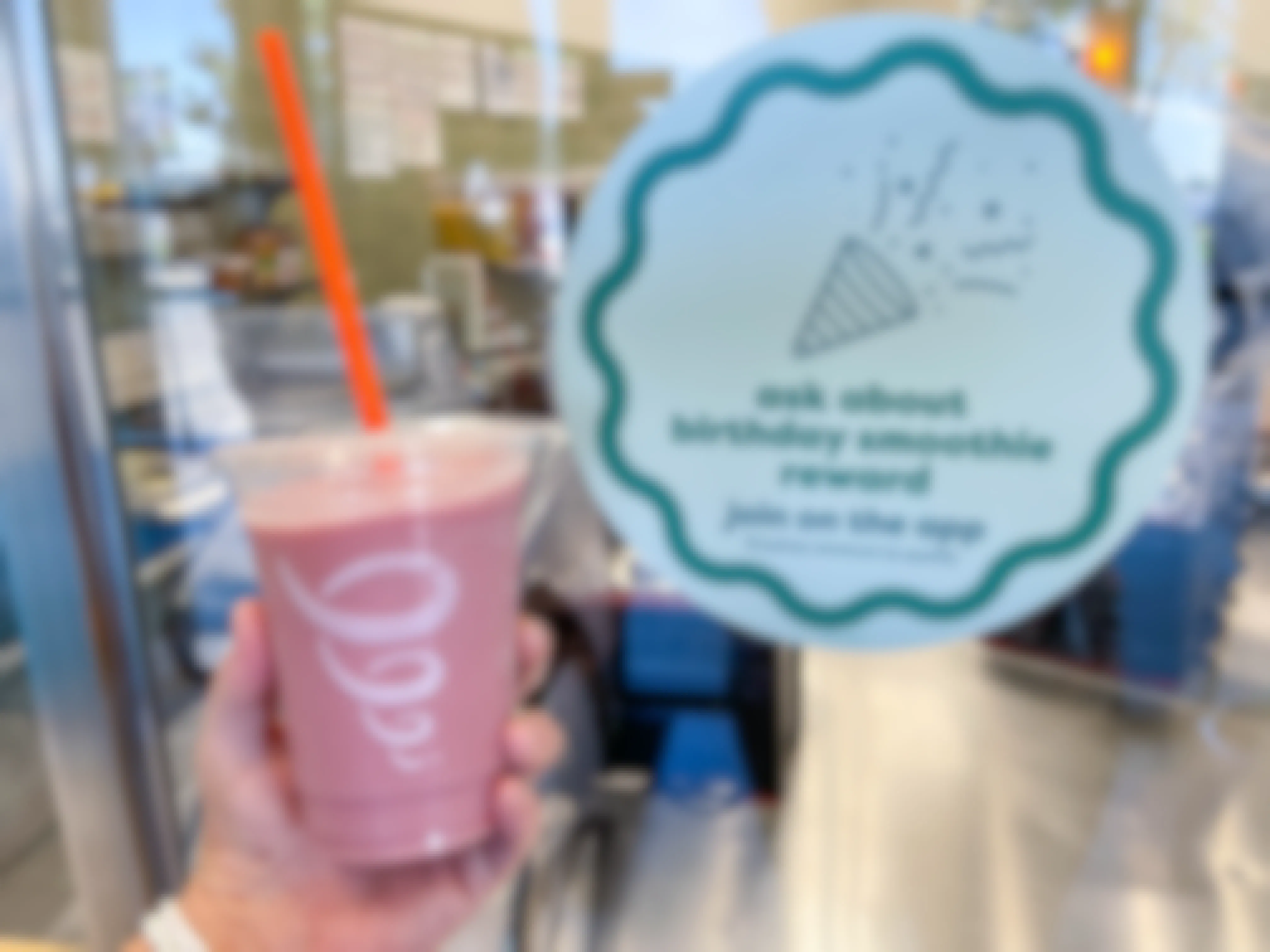 holding a smoothie on one hand and birthday smoothie reward sign 