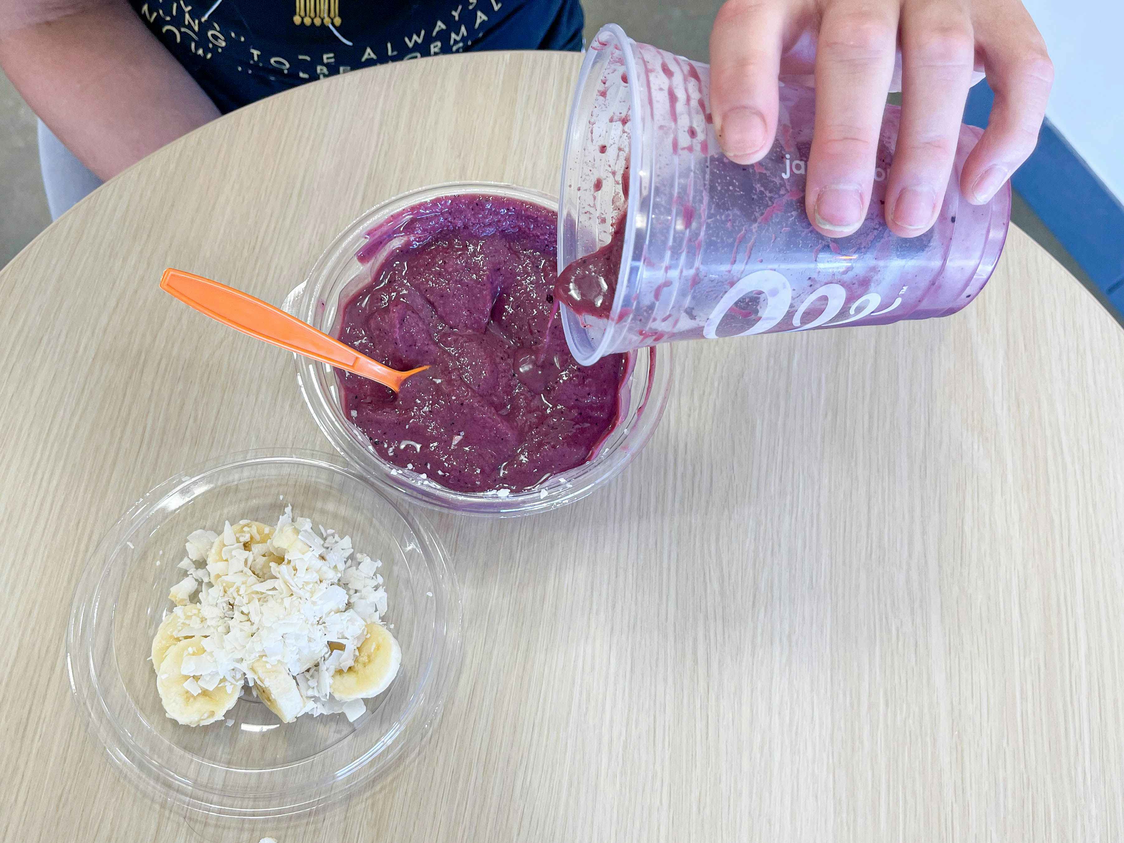pouring an acai smoothie into a bowl with toppings 