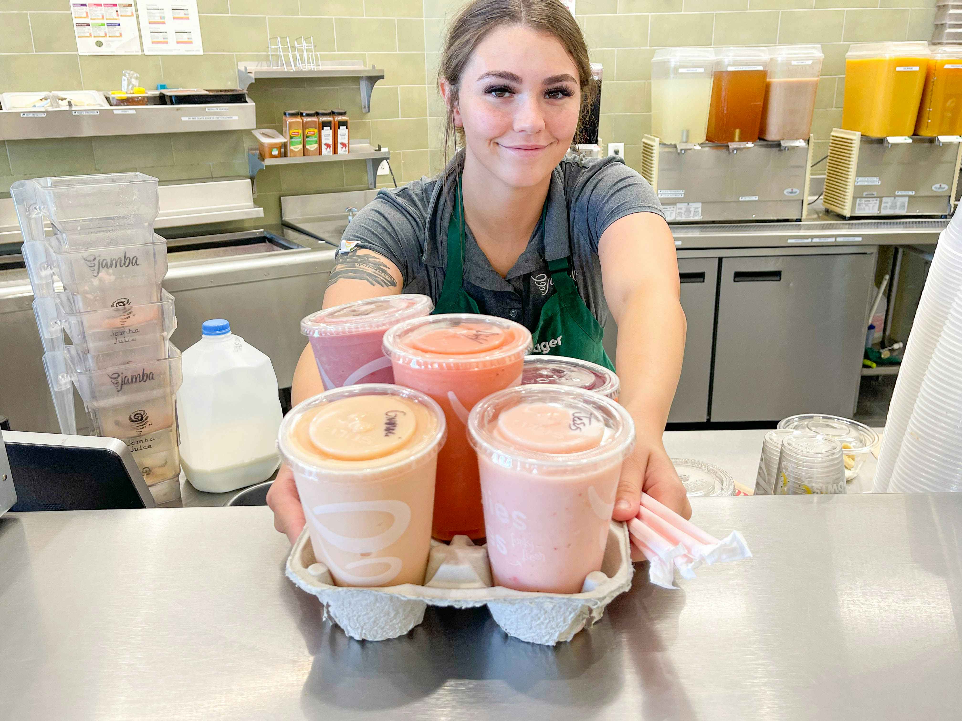 a jamba juice employee giving a bunch of juices 