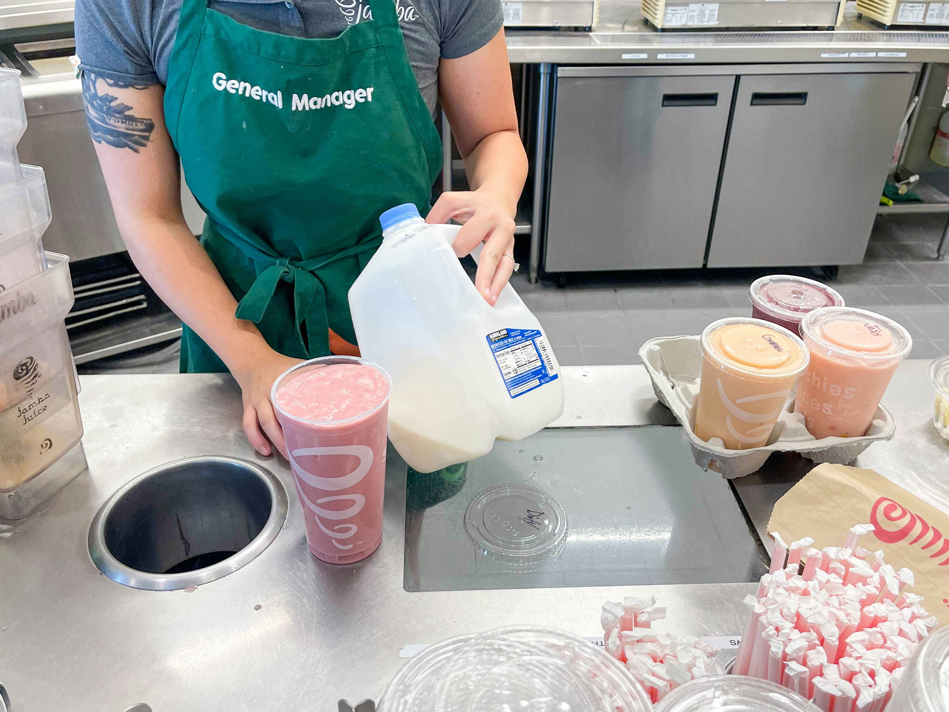 employee holding milk next to smoothie 