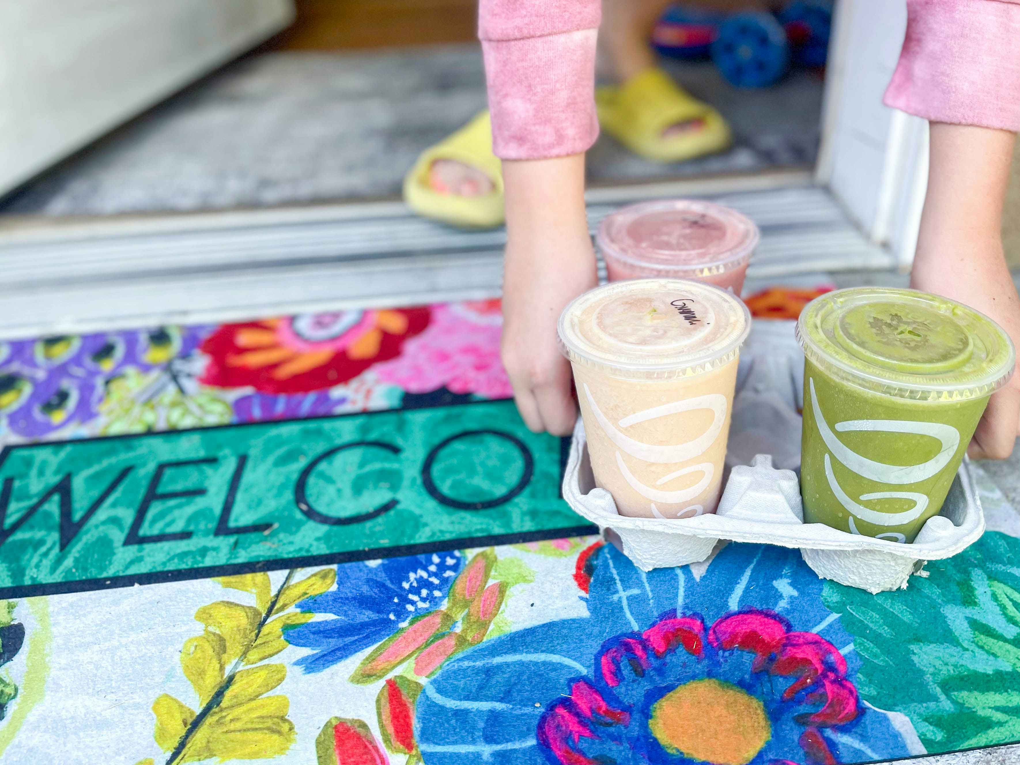 person picking up tray of smoothies from doorstep 