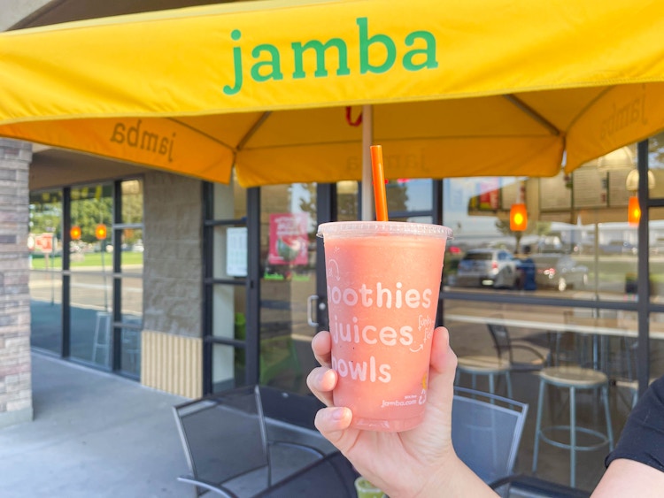 smoothie being held in front of Jamba juice umbrella 