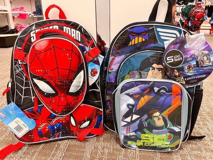 spider man and buzz lightyear character backpacks sitting on a floor in a department store