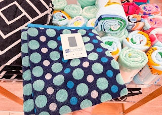 A hand taking a The Big One beach towel off of a shelf at Kohls