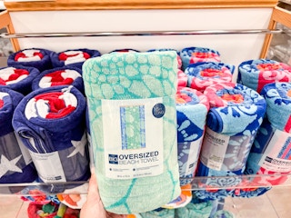 A hand grabbing a The Big One Oversized Beach Towel off a shelf at Kohls