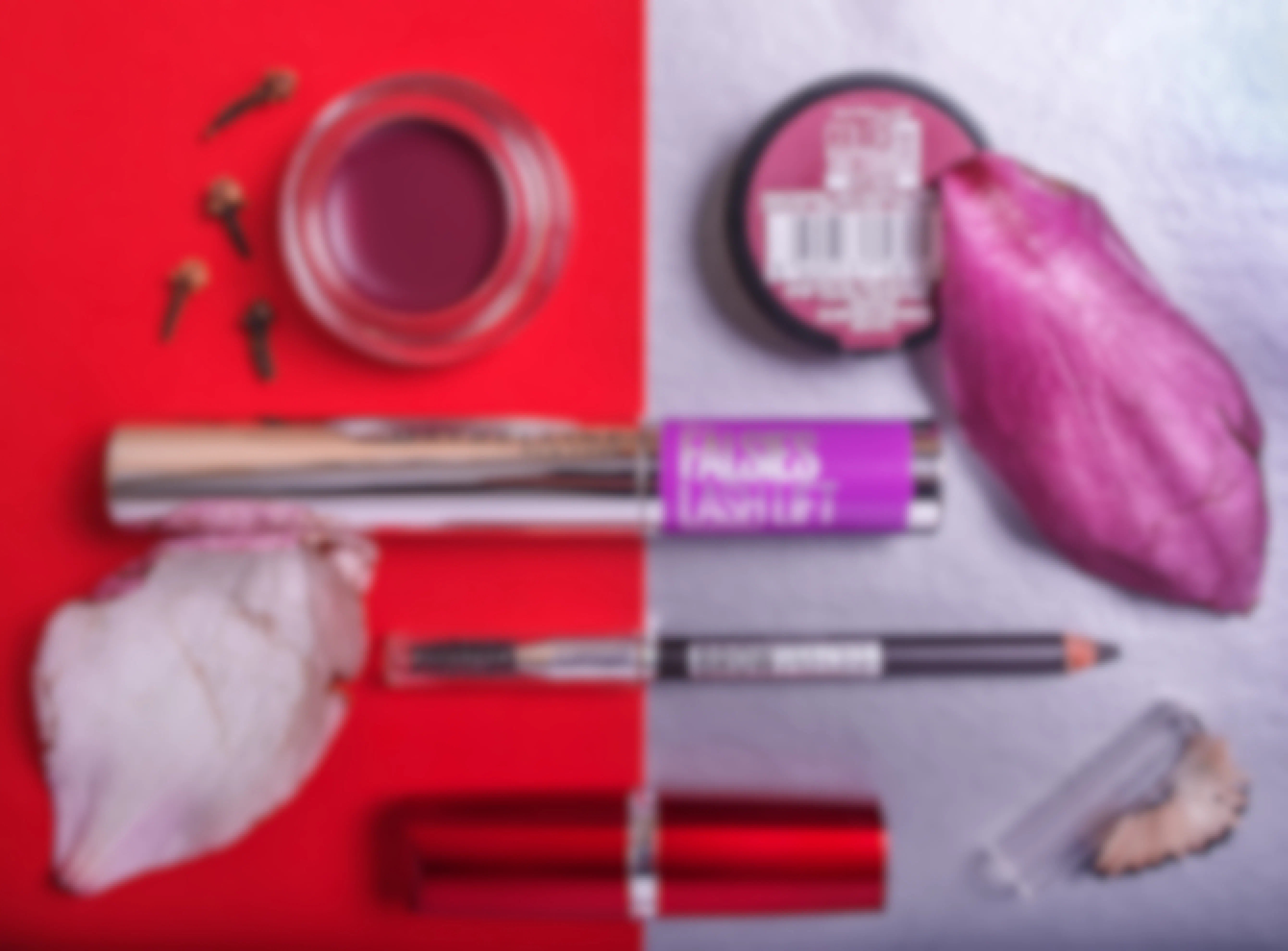 Maybelline makeup laid out on a red and silver background with flower petals.