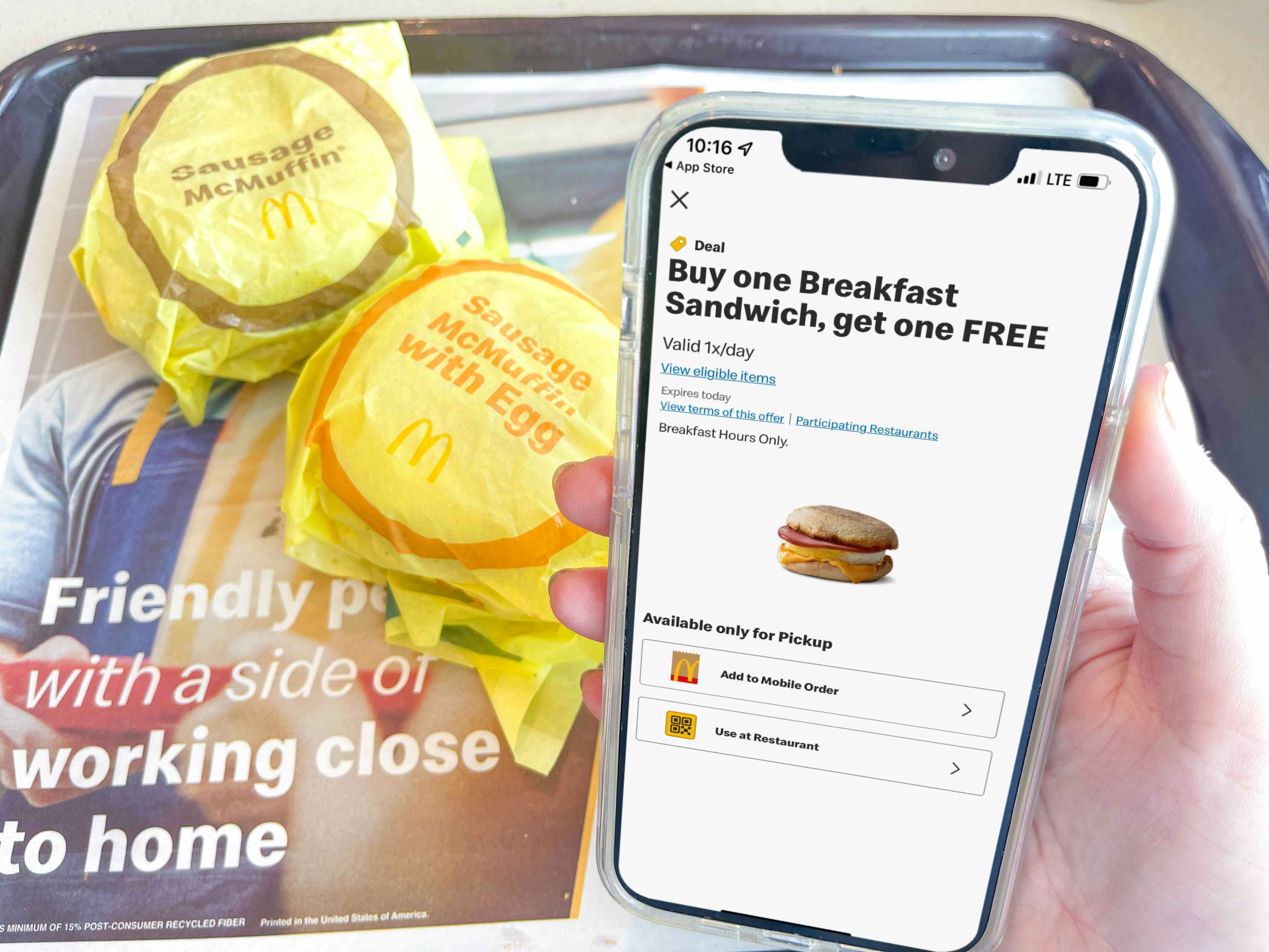 a cellphone with mcdonalds appbeing held in front of 2 mcmuffins 