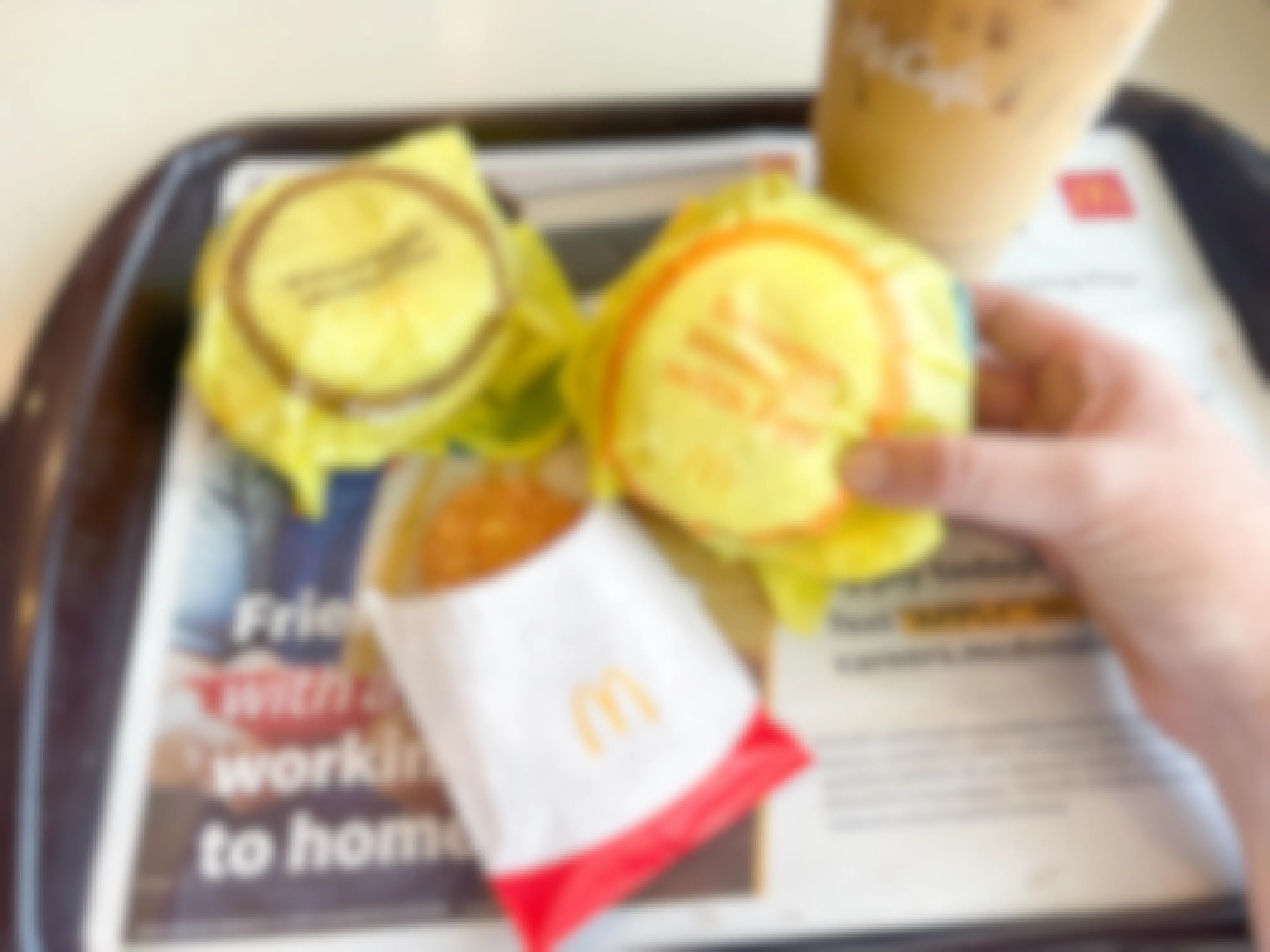 person holding sausage mcmuffin near other mcdonalds breakfast items