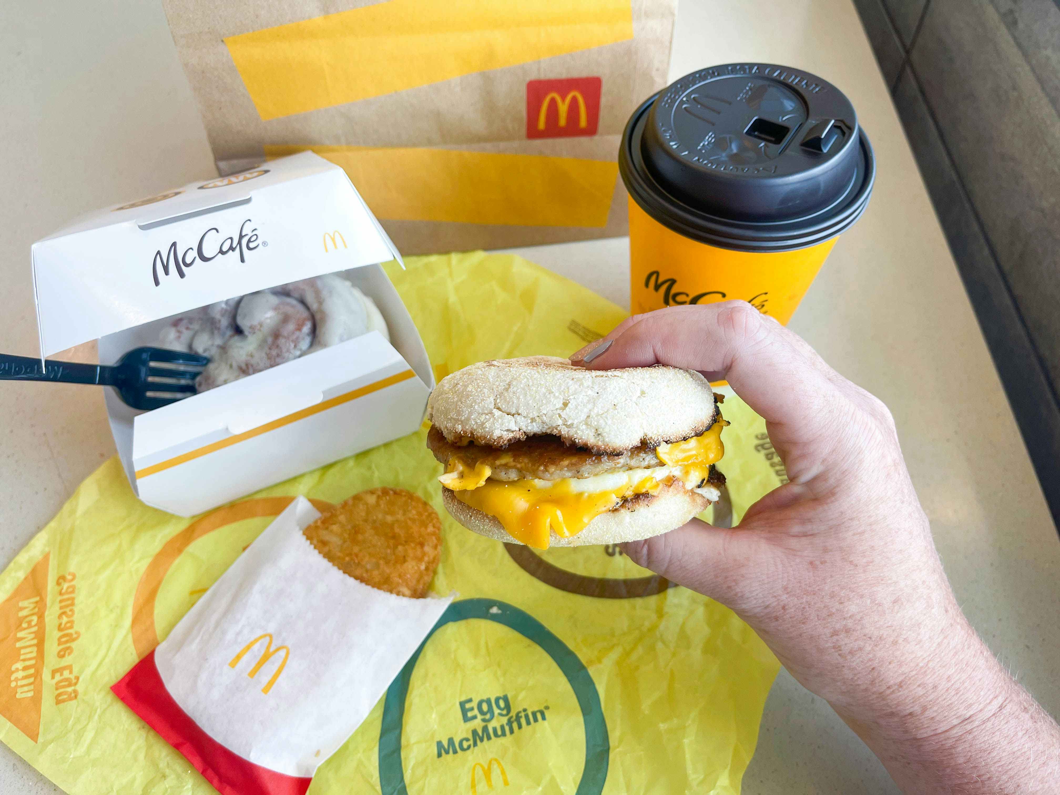 person holding mcdonalds breakfast items at table