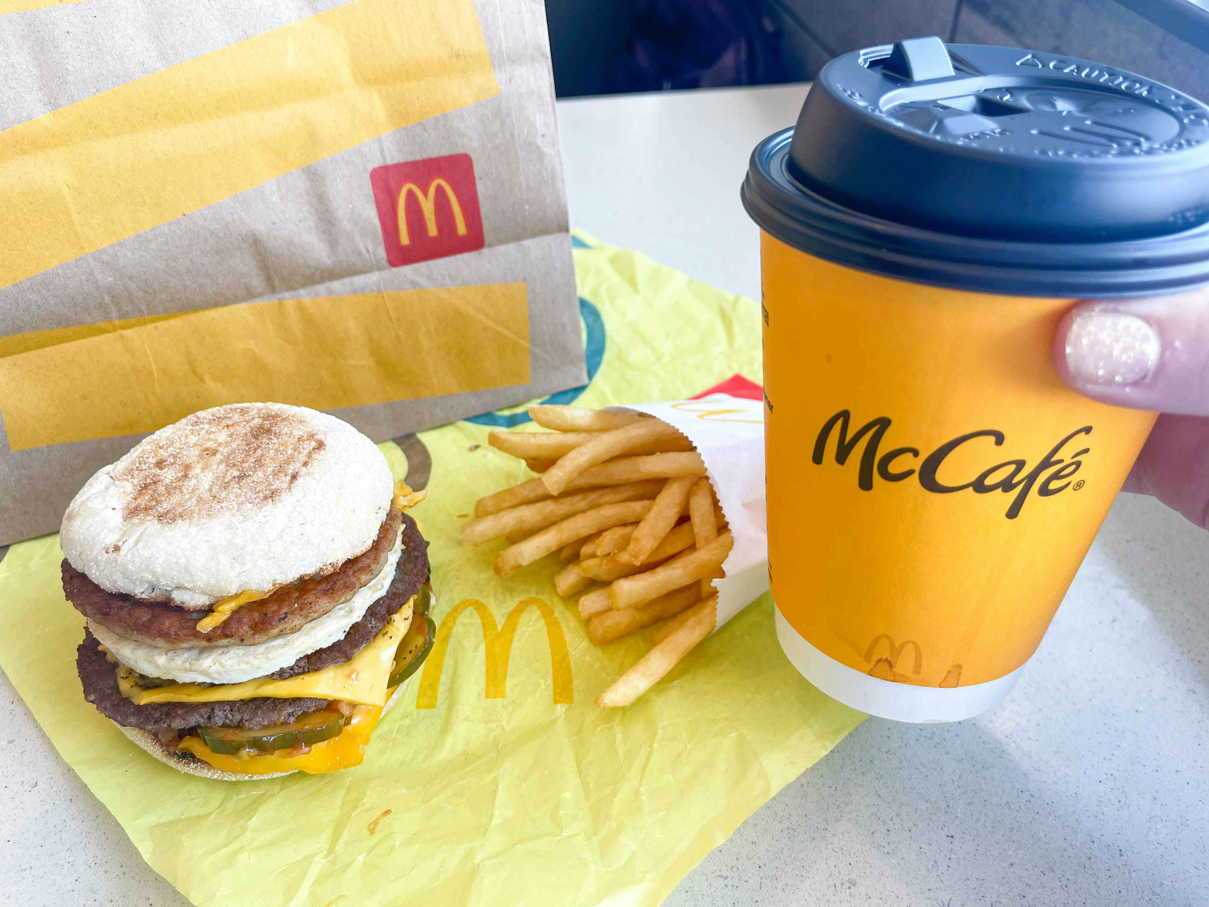 mcdonalds secret menu mcmuffin wand freis on table with mccafe coffee being held 