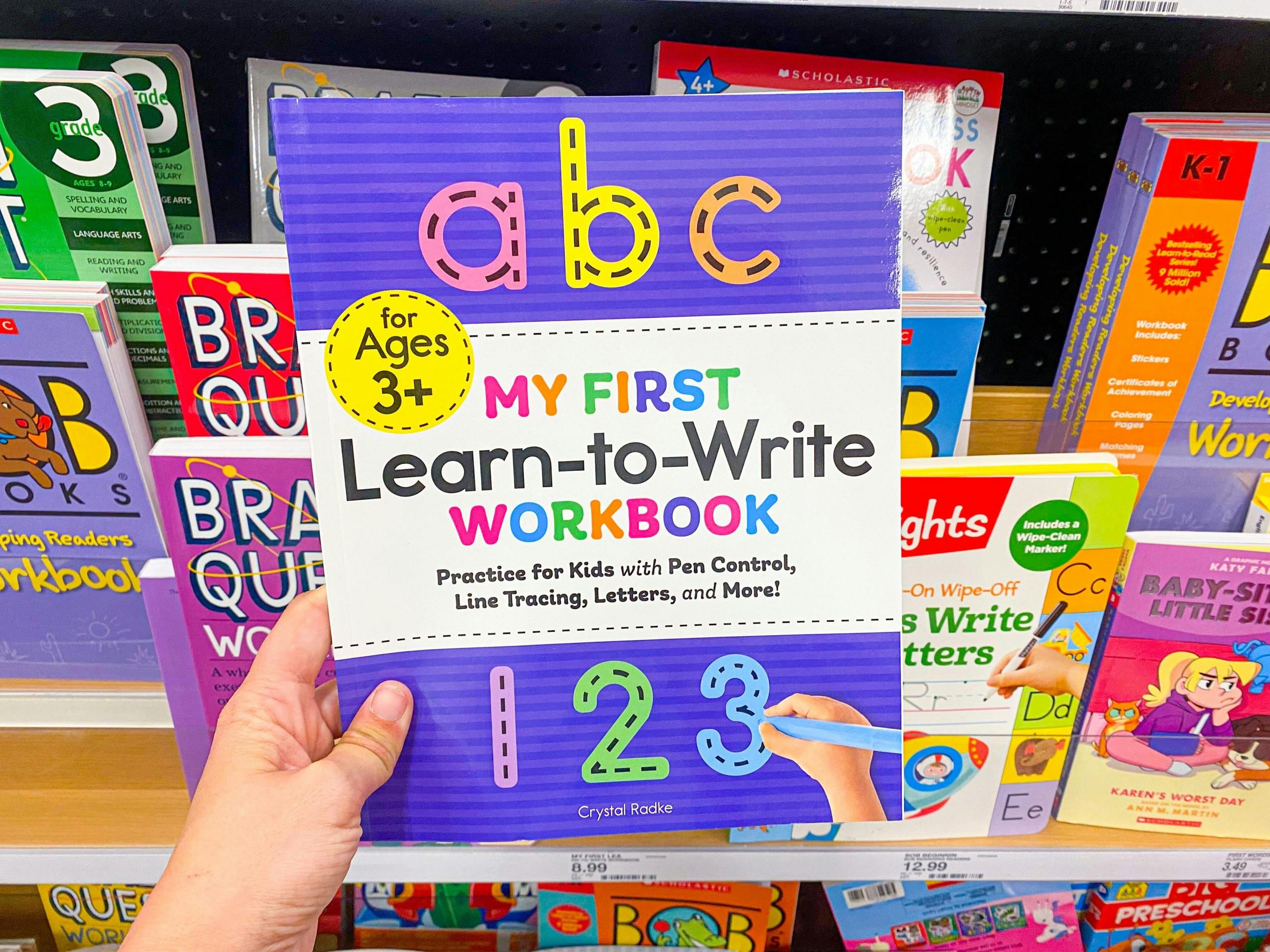 a person holding an ABC my first learn to write book in the children's book aisle at target