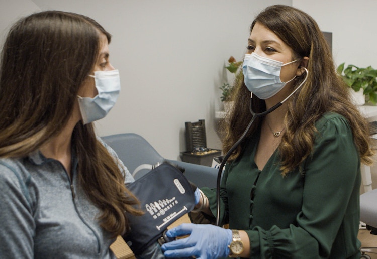 A doctor at a One Medical health clinic measuring a patient's blood pressure.