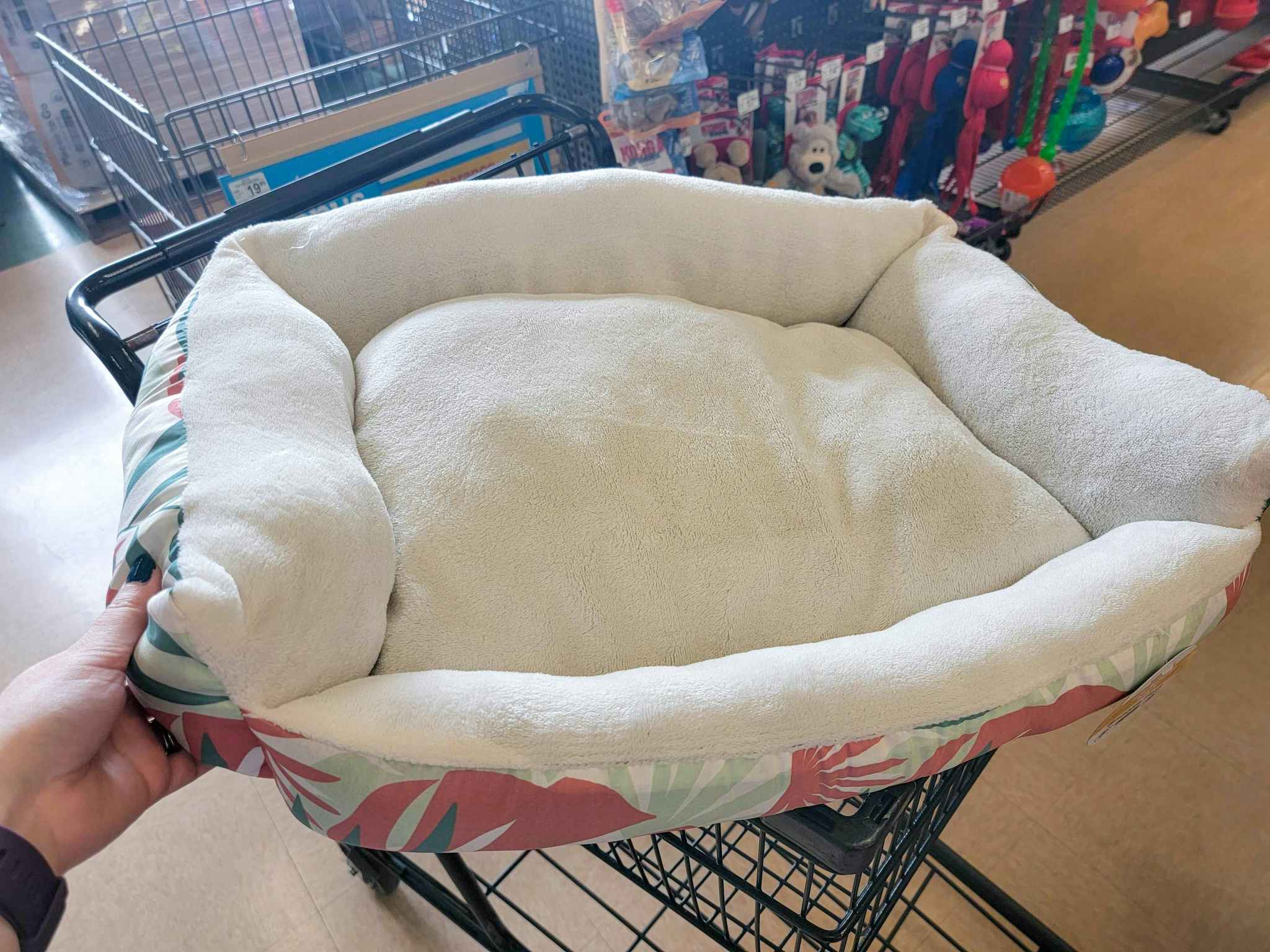 hand holding a palm tree printed dog bed over a cart