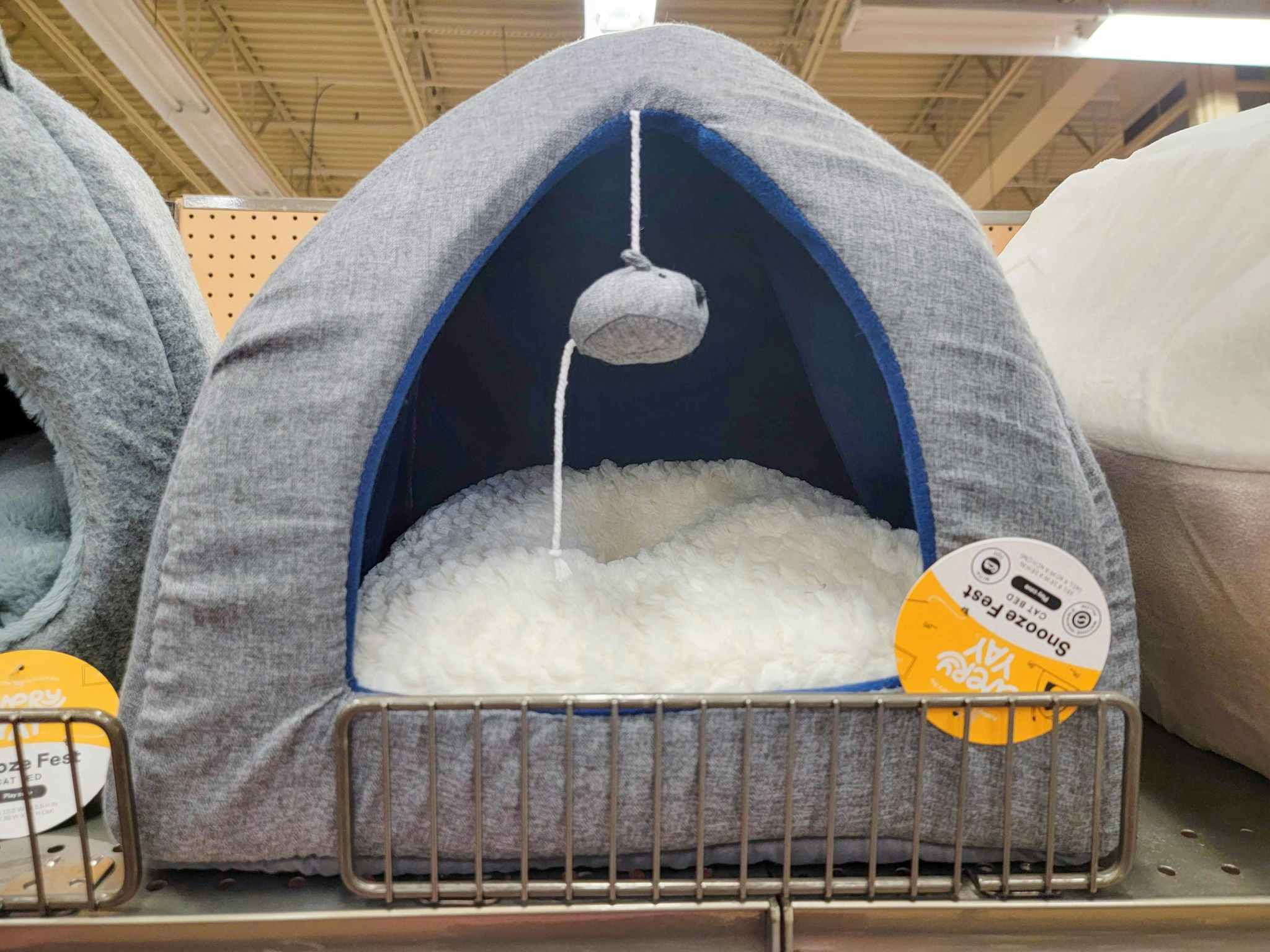 a grey cat igloo style cat bed with a mouse toy hanging from the entry