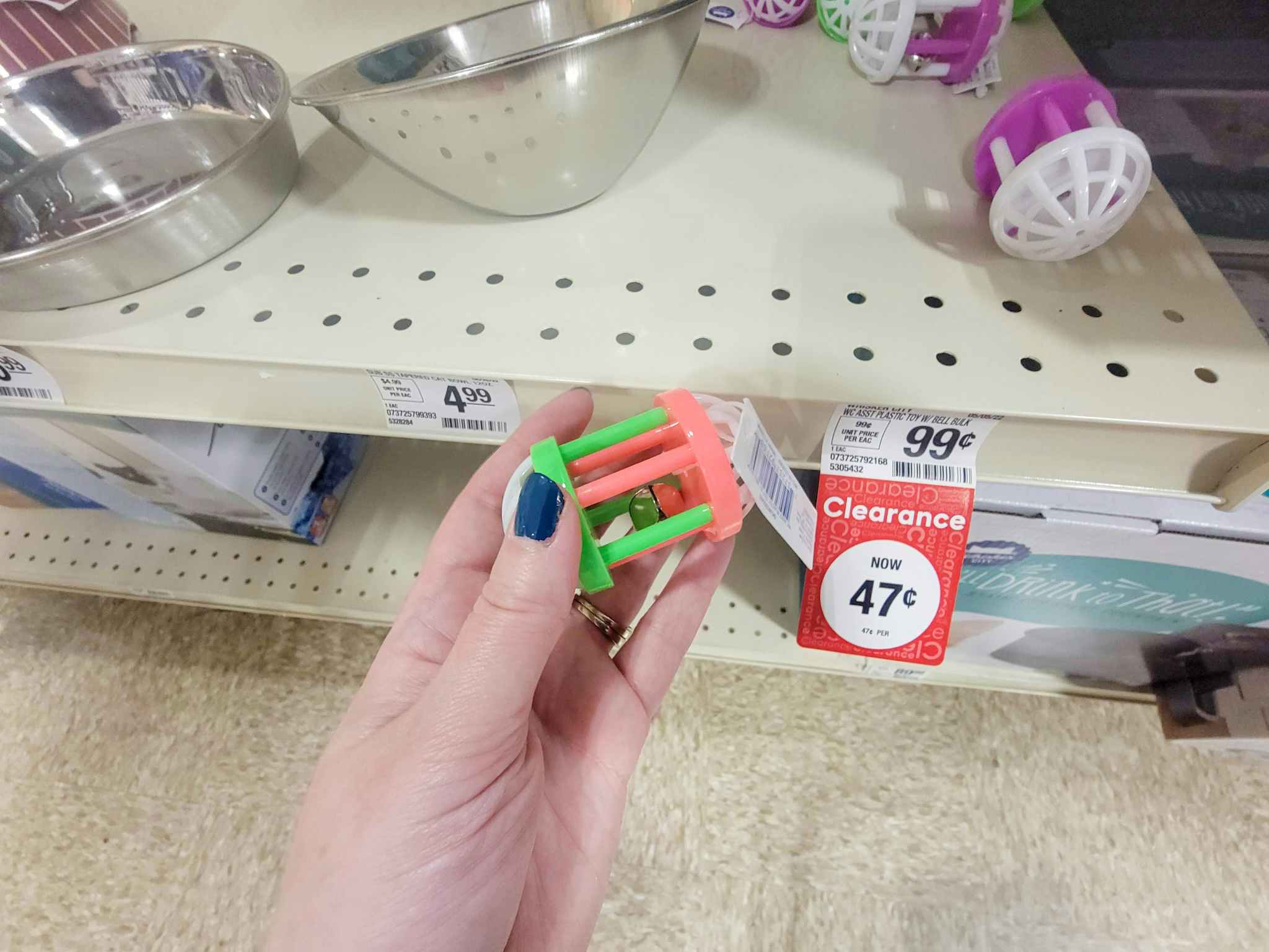 hand holding a small cat toy with a bell in it