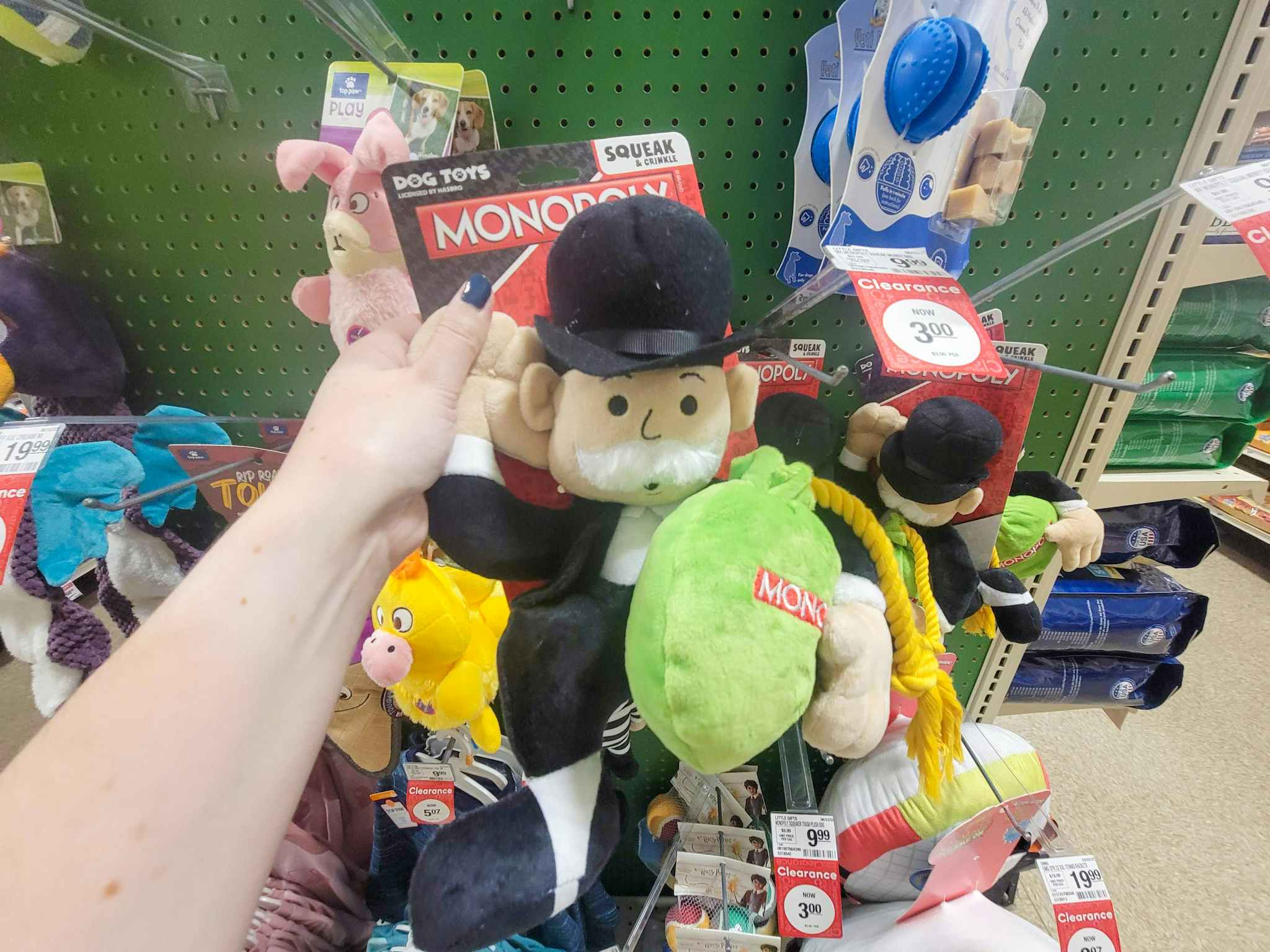 hand holding a monopoly man dog toy holding a bag of money