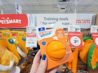 hand holding an orange dog toy ball