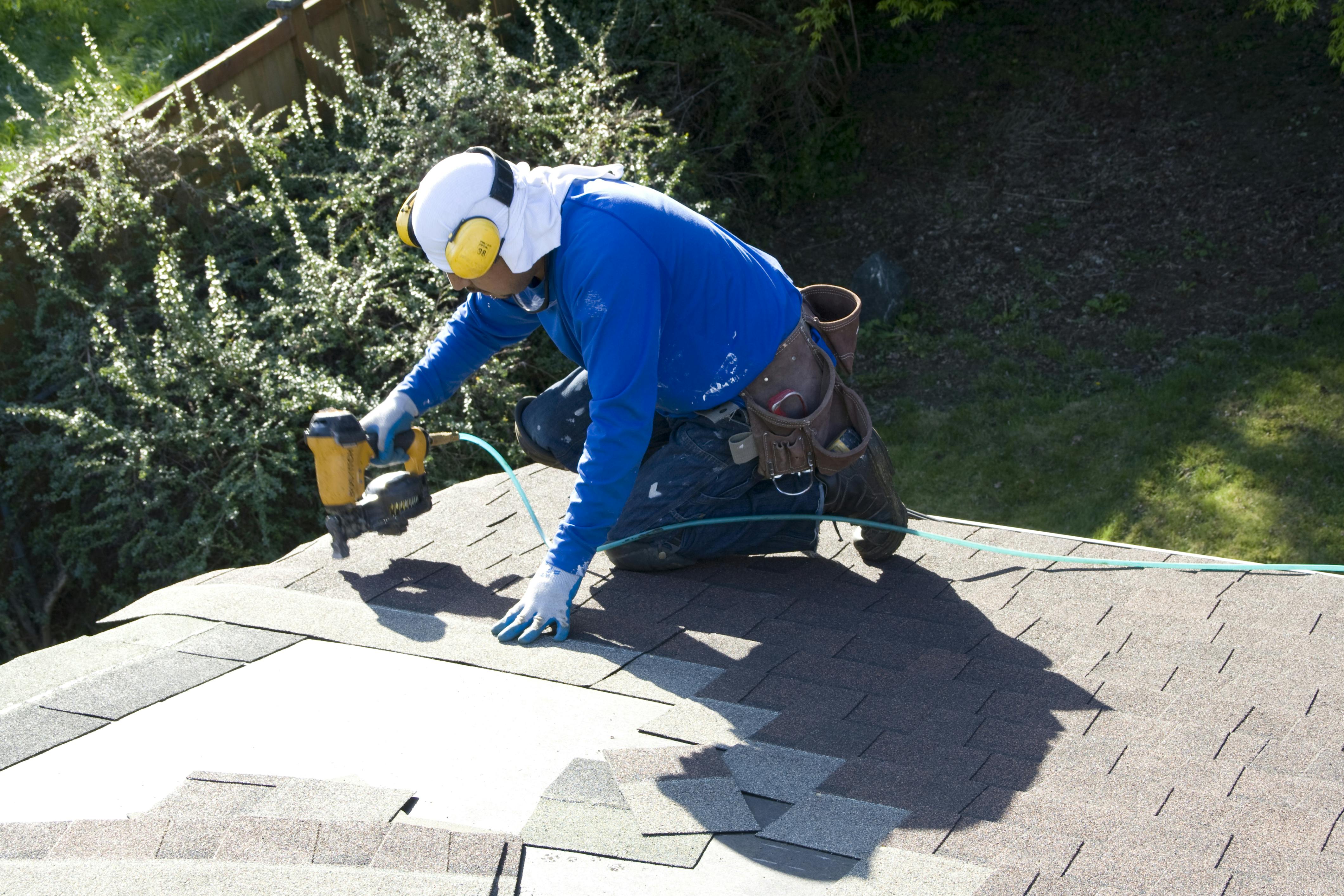 A man installing shingles on a new roof.