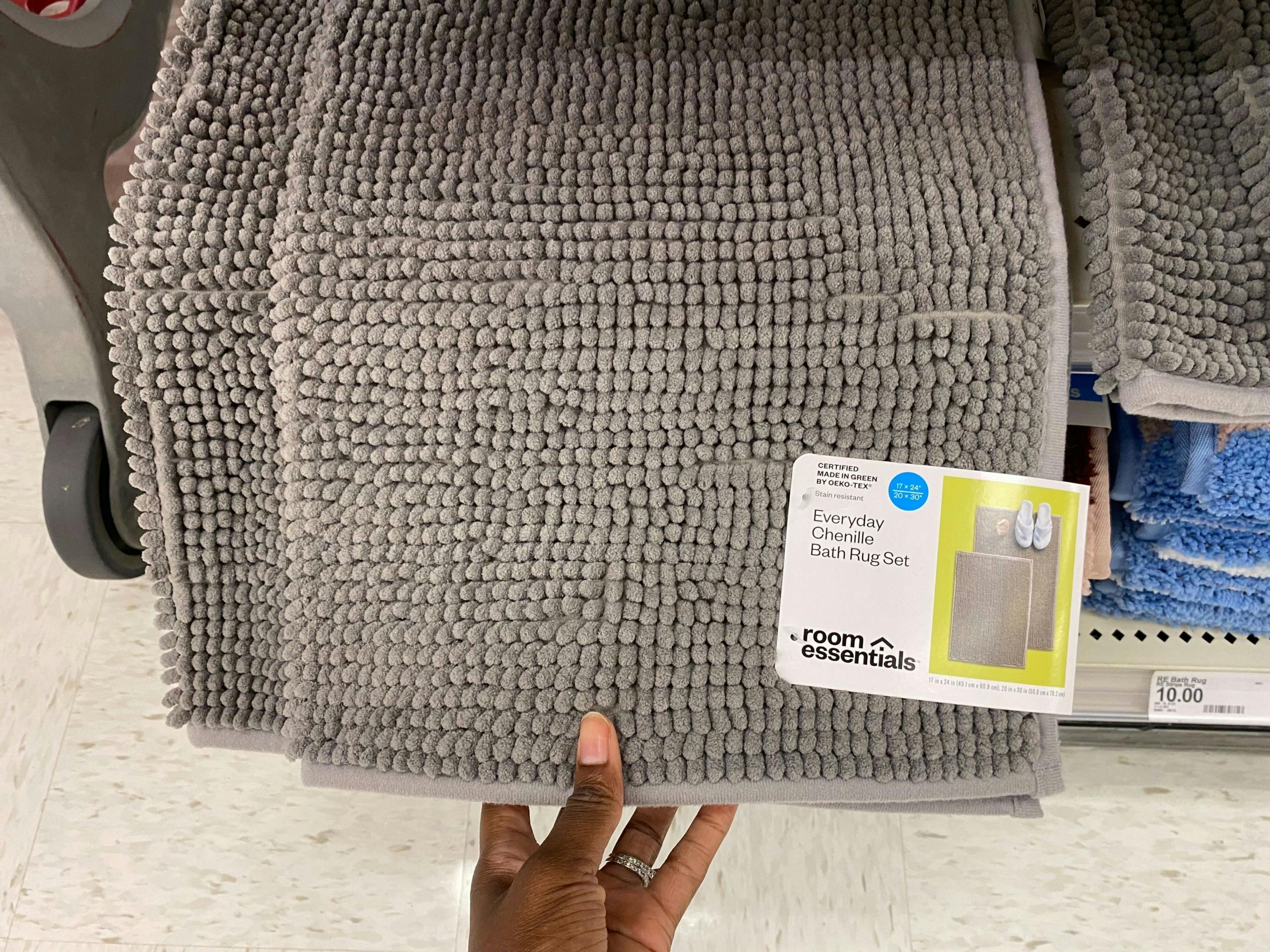 A person's hand taking a 2-pack of everyday chenille bath rugs from a Target shelf
