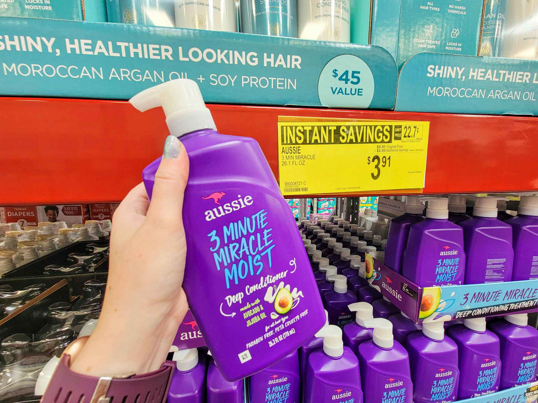 hand holding a large bottle of aussie 3 minute miracle deep conditioner
