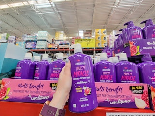 hand holding a bottle of aussie multi miracle conditioner