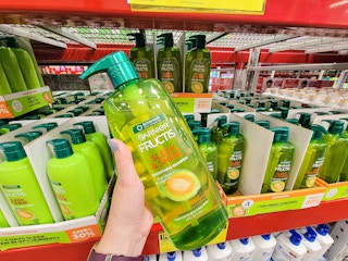 hand holding a large bottle of garnier fructis sleek & shine shampoo