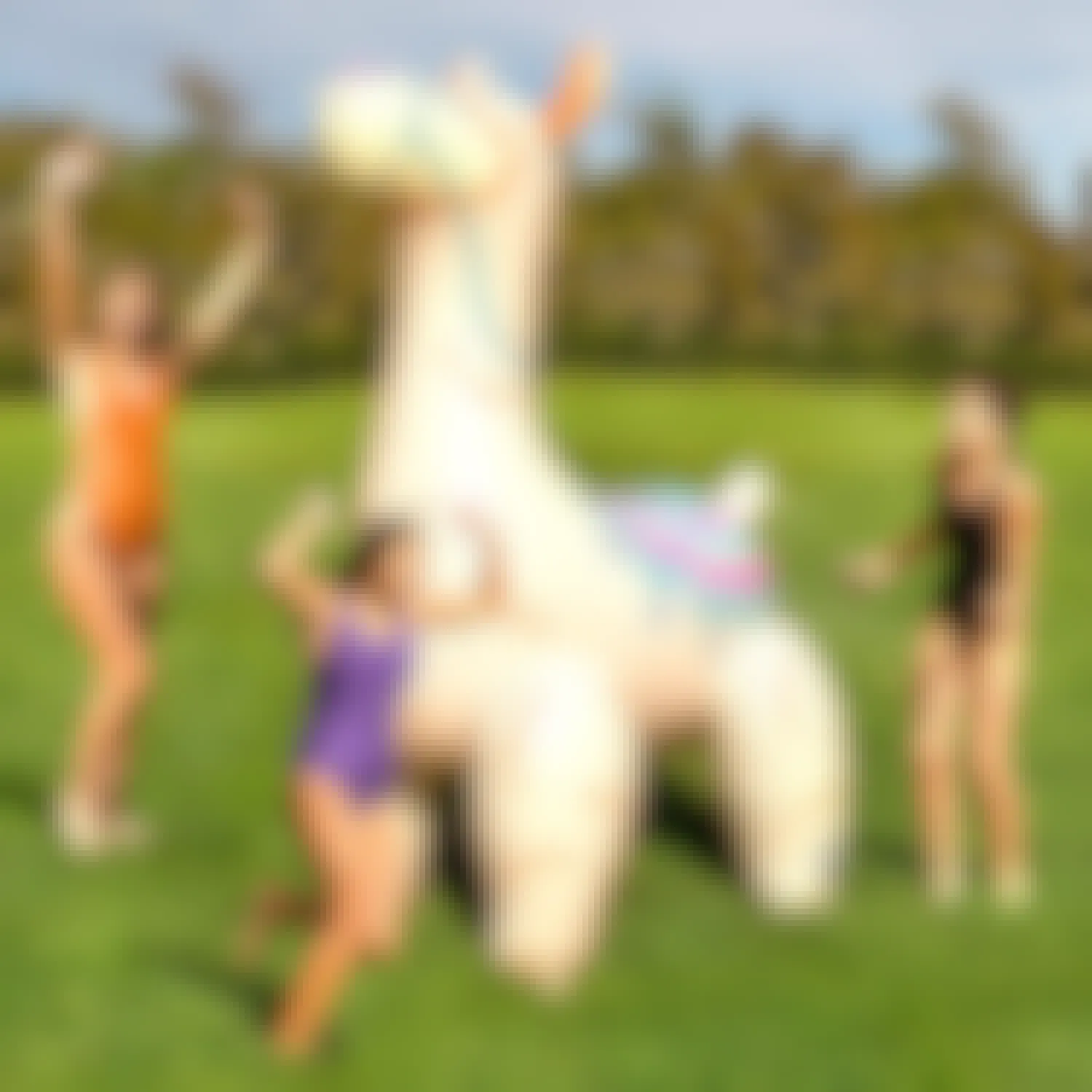 3 people playing around a giant inflatable llama sprinkler