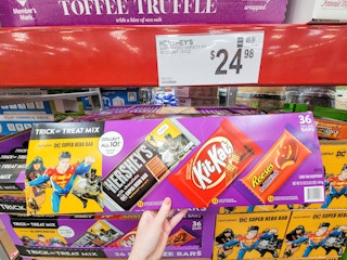 hand holding a box of full size hersheys, reeses, and kit kat bars for halloween