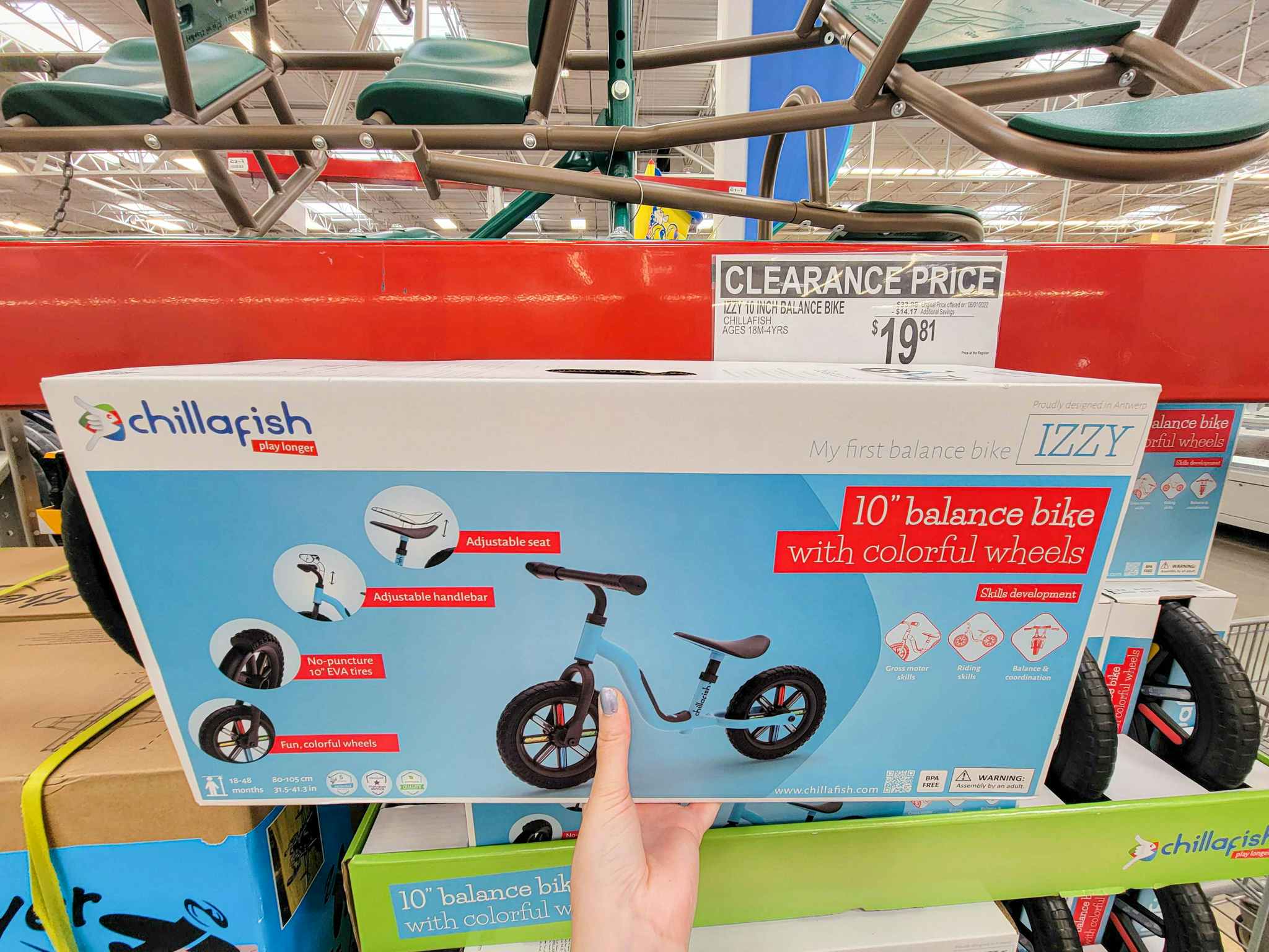 hand holding a balance bike with colorful wheels