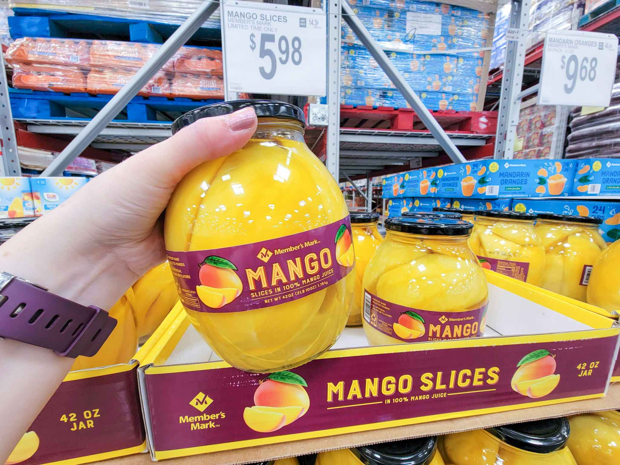 hand holding a large jar of mango slices