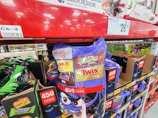 hand holding a large bag of halloween candy with twix, milky way, and other mars brands