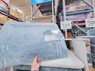 hand holding up a light blue memory foam bath mat